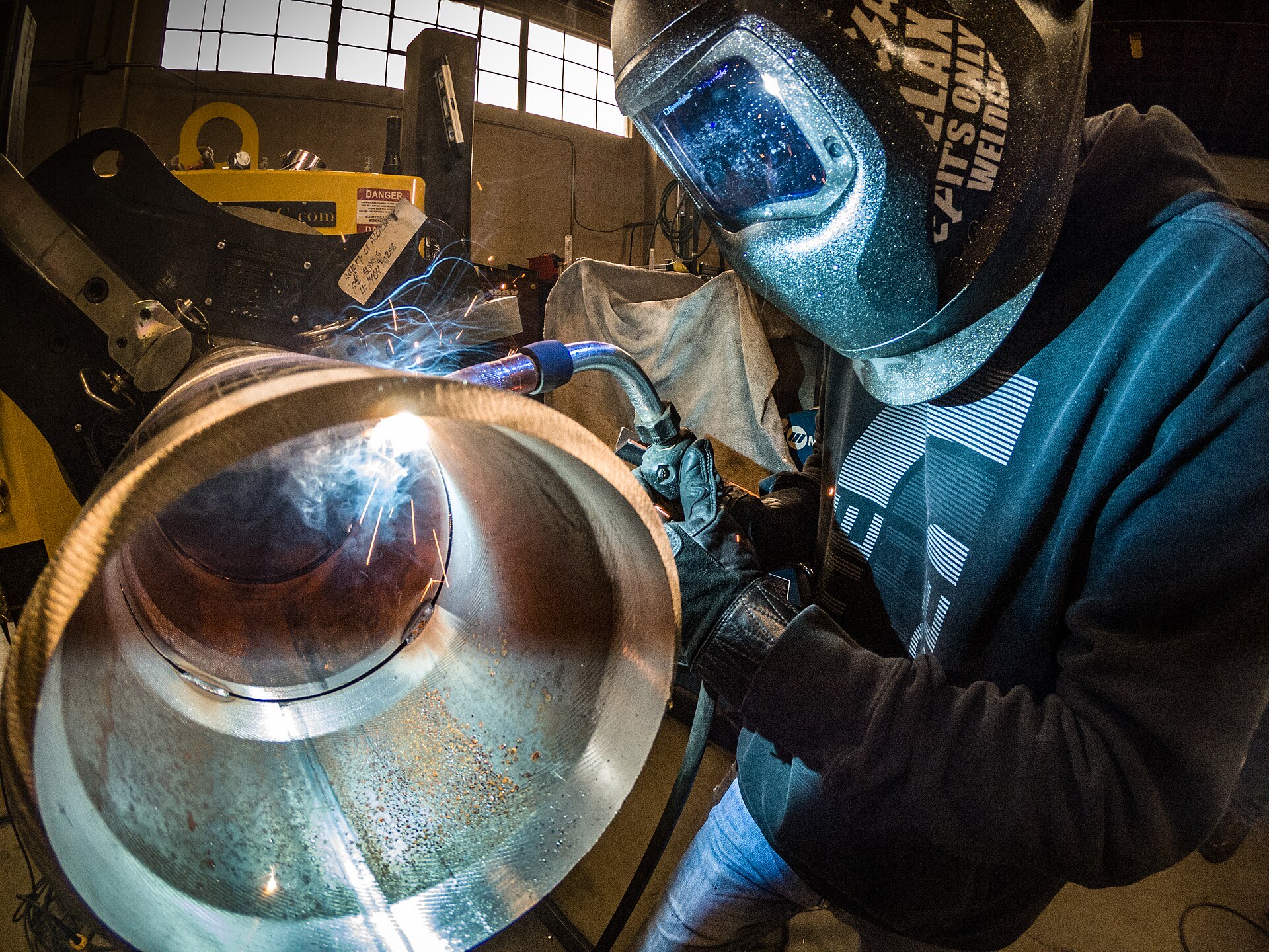 Welder in a mask welding the joint on a large pipe section